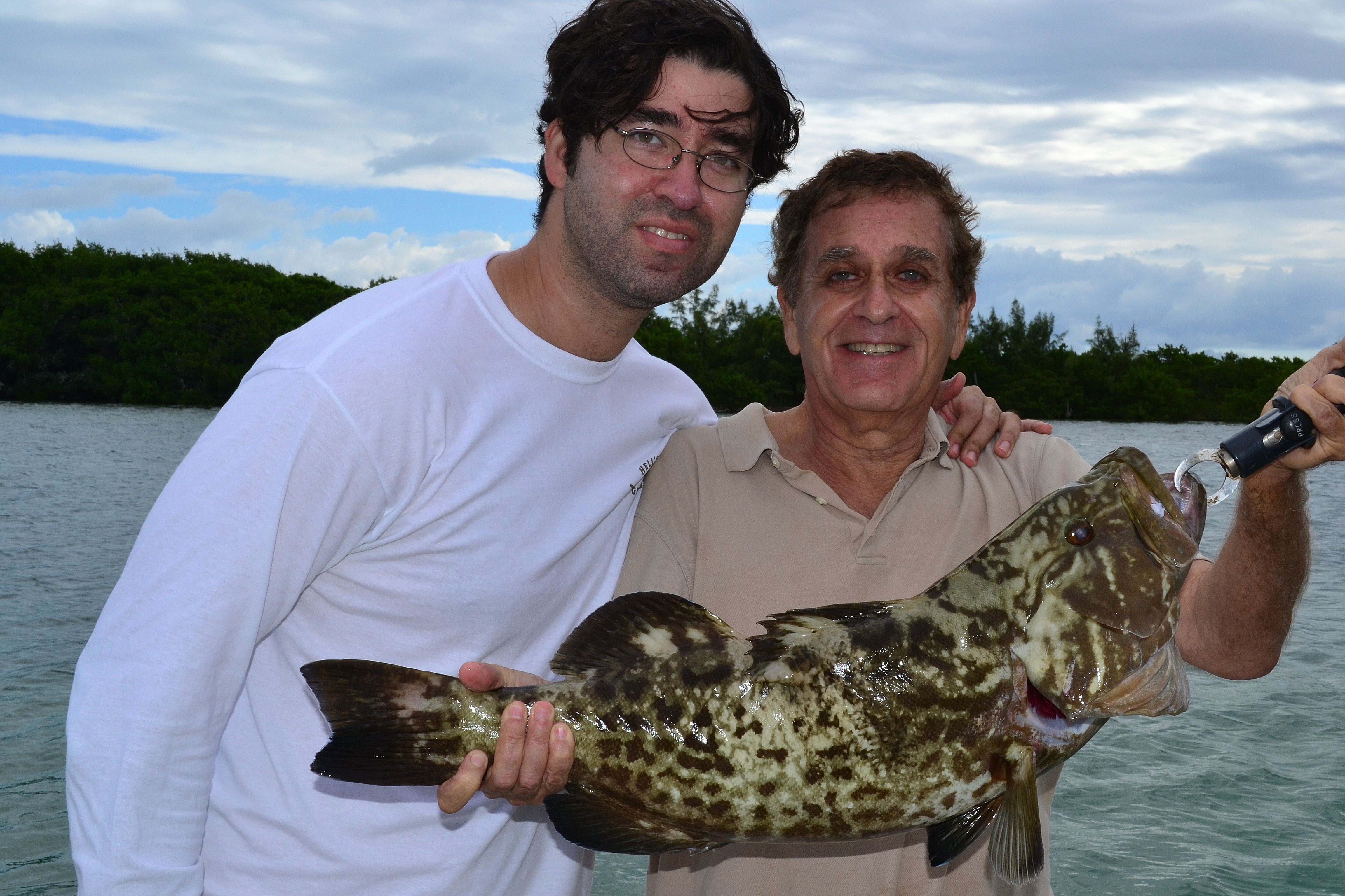 Two anglers holding a large grouper caught on a full day fishing charter in Biscayne Bay Miami